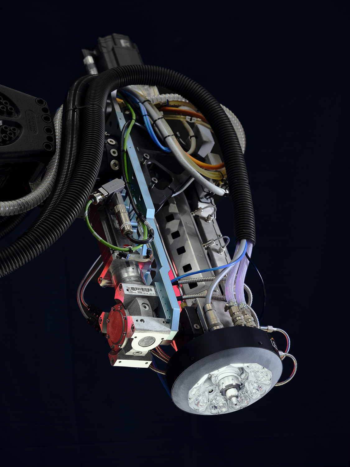 DEMEX retrofit hardware installed around an extrusion AM head with routed cables and cooling lines